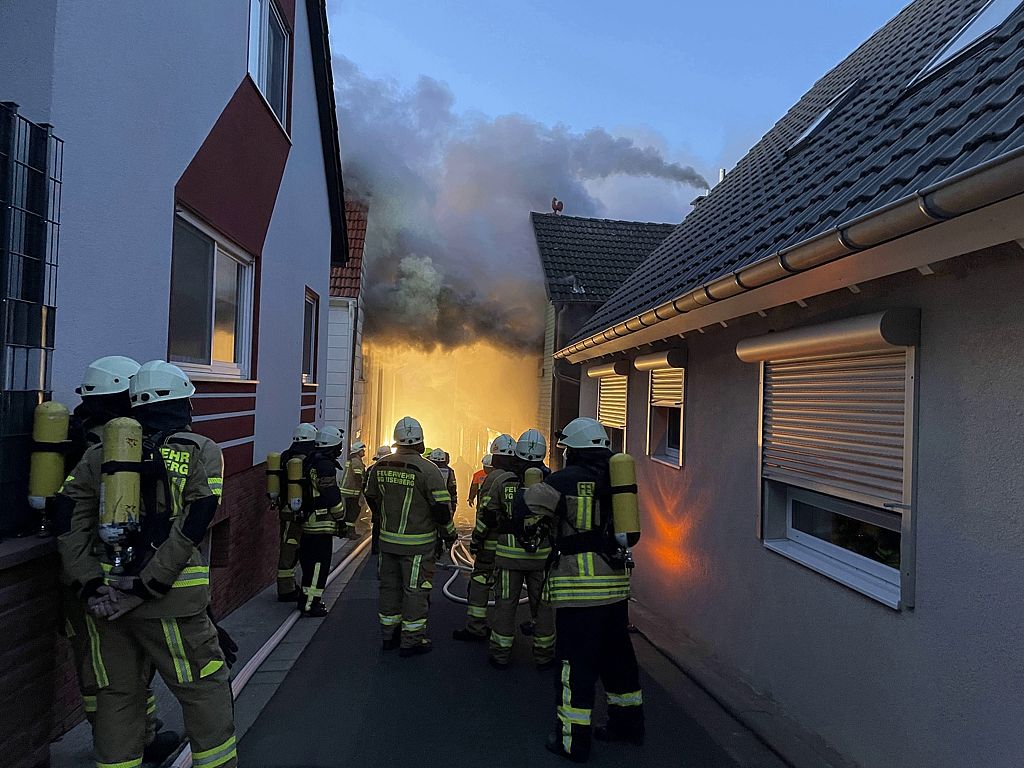 Einsatzkräfte der Feuerwehr vor brennendem Gebäude