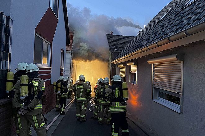 Einsatzkräfte der Feuerwehr vor brennendem Gebäude